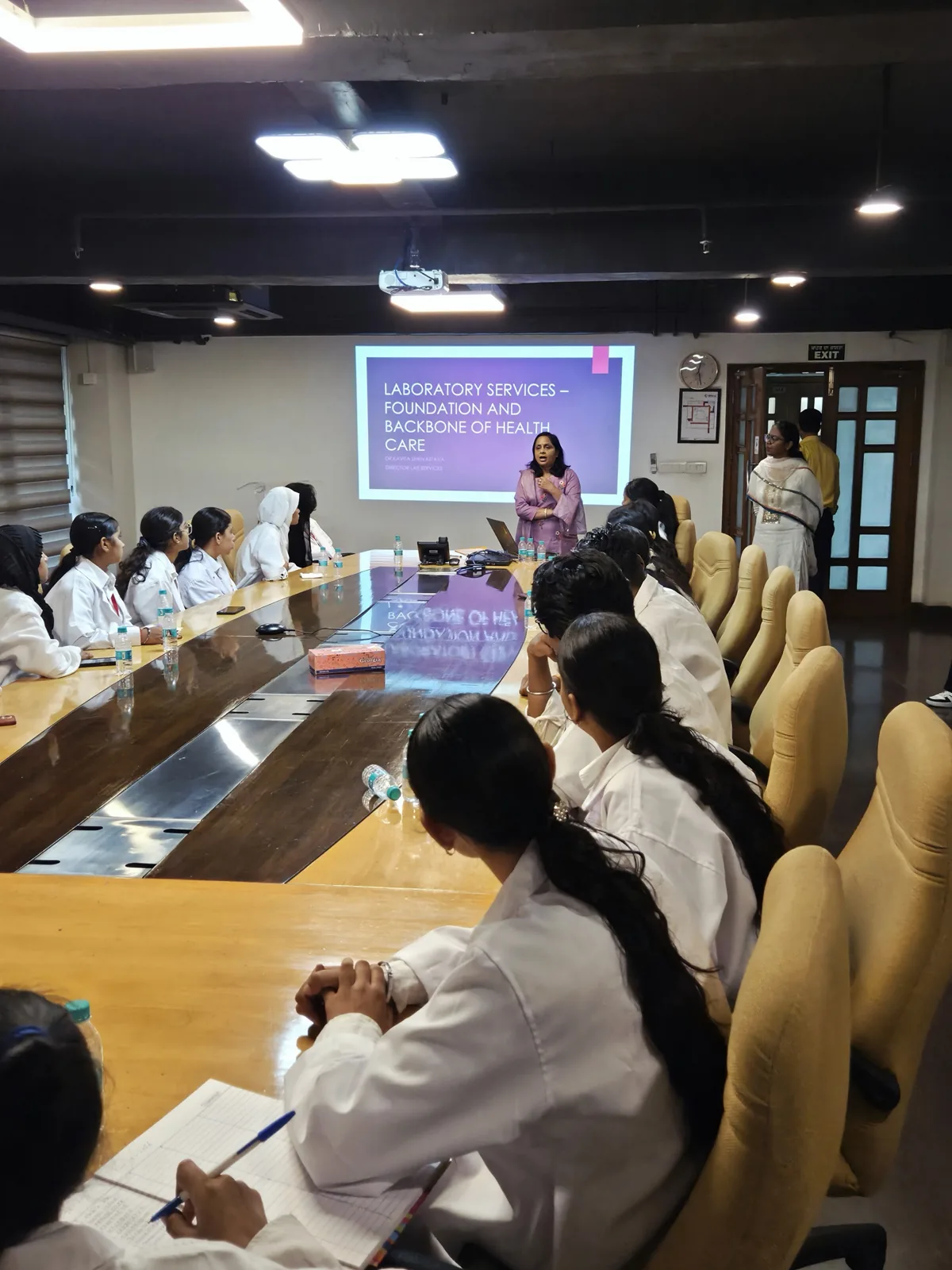 Students in white lab coats listen to the Laboratory Services session at SPS Hospitals