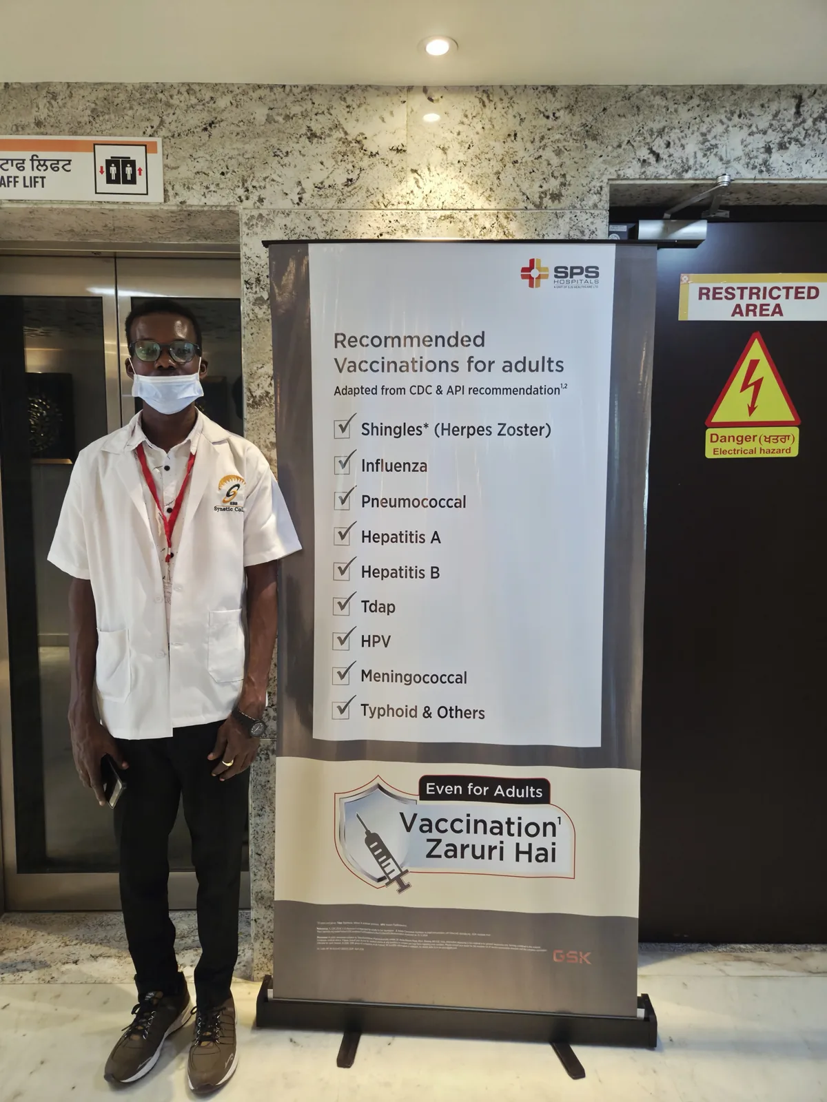 An SBS student beside an SPS Hospitals adult vaccination awareness display